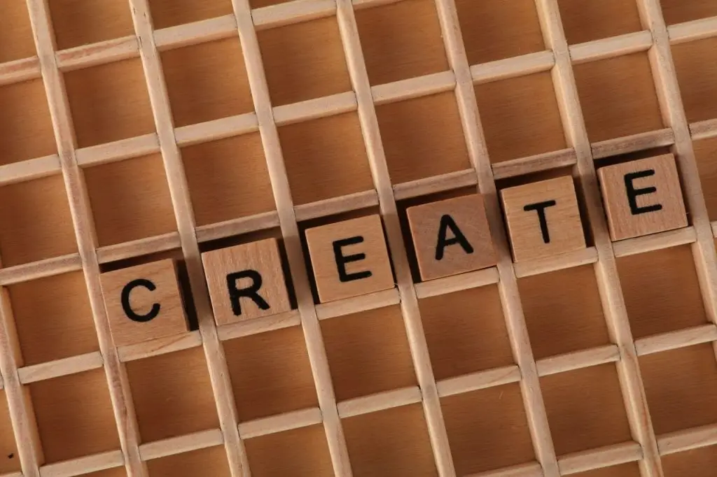 Wooden letter blocks spelling 'CREATE' in a wooden grid background.